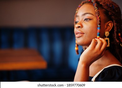 Face portrait of lovely african american woman with dreadlocks at cafe. Beautiful cool fashionable black young girl indoor.