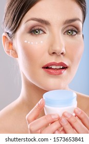 Face Portrait Of Woman With Clean Skin, White Dots Under Eye. Girl Holding Cream Jar.