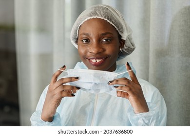 Face Of Pretty Smiling Young Black Nurse Taking Off Medical Mask From Sweaty Face