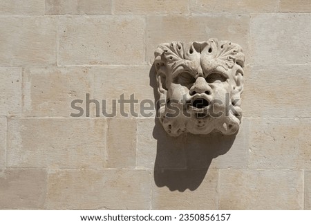 The face protrudes from the white stone wall. Background with copy space. Dubrovnik Croatia. Selective focus