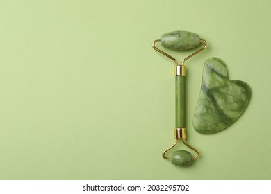 Face roller and gua sha on green background
