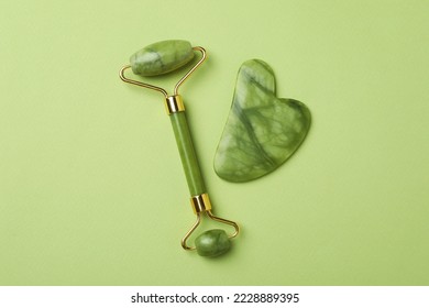 Face roller and gua sha on green background