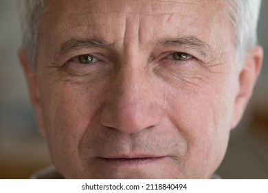Face of serious mature elder man with brown eyes, wrinkles. Close up front cropped shot of male retiree, senior pensioner looking at camera. Older age, elderly health care concept