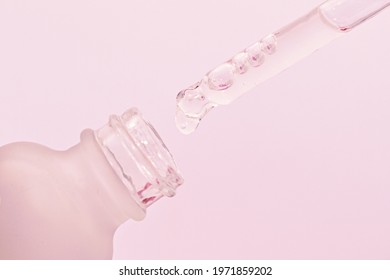 Face Serum Drop With Glass Dropper Bottle Jar With Pipette On Pink Background Close Up Macro