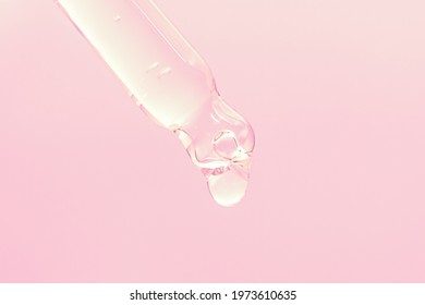 Face Serum Drop With Glass Dropper Pipette On Pink Background Close Up Macro