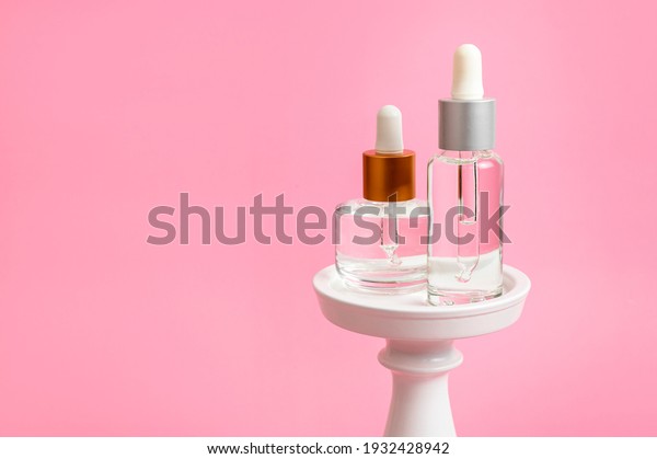 Face serum with pipette in glass bottle on\
white podium on pink background. Anti-aging serum, moisturizing\
serum for beautiful skin. Facial liquid serum. Branding layout.\
Clean packaging of cosmetics\
