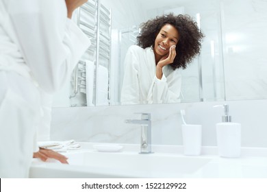 Face Skin Care. Girl Removing Makeup With Cosmetic Cotton Pad At Bathroom. Closeup Portrait Of Beautiful Smiling African Woman With Afro Hair Cleaning Facial Skin With White Pad