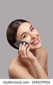 Face skin care. Smiling woman using facial oil blotting paper portrait. Closeup of beautiful happy girl model with natural makeup using oil absorbing sheets, beauty product