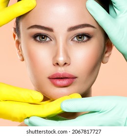 Face skin check before plastic surgery. Beautician touching young woman face. Doctor in medicine gloves checks a skin before plastic surgery. Beauty treatments. Colorful image