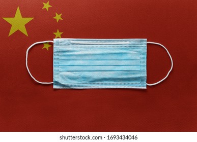 Face Surgical Medical Blue Mask Lying On China National Flag. Illness, Coronavirus In China, Concept Photo
