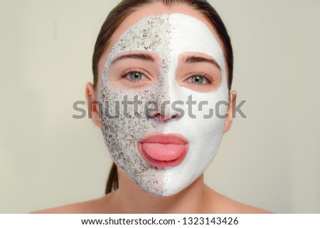 The face of the woman with a cosmetic mask. The concept of spa, beauty and skin care. Girl teases and shows tongue
