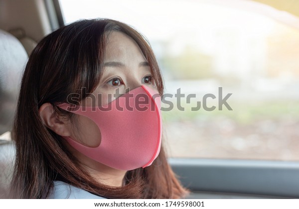 The face of a woman wearing a mask in a car\
traveling to work in New\
Normal.