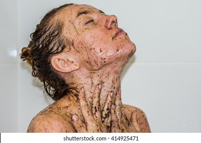Face of young beautiful sexy girl with long hair girl who takes a bath naked in the spa procedures, wellness dealt a protective mask of coffee for skin health