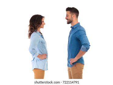 Face To Face Young Casual Couple Standing With Hands On Waist On White Background