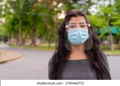 Face of young Indian woman wearing mask and face shield at the park outdoors