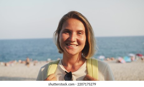 Face Young Sunshine Woman Looking At Camera Smiling Standing Outdoor On Sea Background. Summer Natural Beauty Portrait Of Woman Tourist.