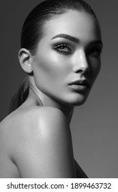 Face Of A Young Woman With Bright Makeup And Gathered Hair In A Sleek Ponytail. Black And White Photography.