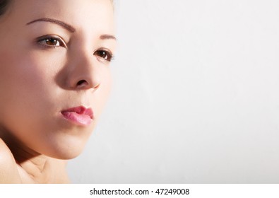 Face of young woman over gray background. Looking at camera