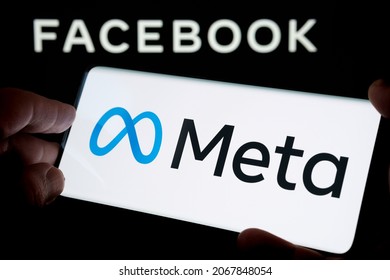 FACEBOOK META company logo seen smartphone hold in hand with  blurred Facebook inc. logo on laptop screen behind. Selective focus. Stafford, United Kingdom, October 28, 2021.