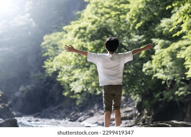 Faceless image of a boy taking a deep breath or relaxing in the forest