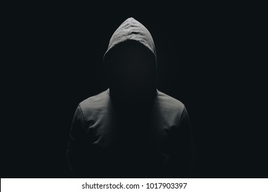 faceless man in hoodie standing isolated on black