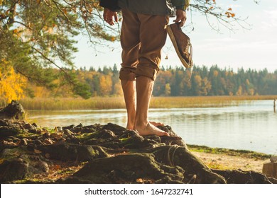 faceless man standing barefoot on lake river bank looking afar summer holidays. Unrecognizable tourist ready to travel walk relaxing before trekking. Travel tourism vacation. Belarus sight-seeing