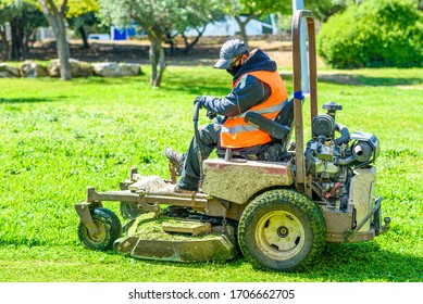 Faceless man wear safety masks as a precaution during outbreak the Coronavirus Covid 19 during mows the grass with lawn mower. - Shutterstock ID 1706662705