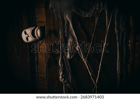 Faceless monster in white mask with sharp teeth looking out from behind old wooden door, creepy Halloween horror atmosphere.