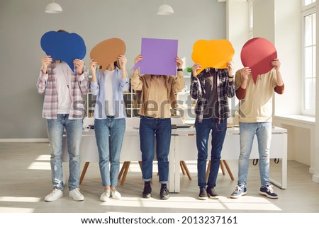 Faceless people sharing message or expressing opinion in anonymous survey. Group of unrecognizable young college or university students covering faces with multicolored paper mockup speech bubbles