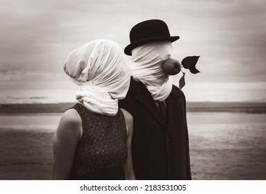 Faceless portrait of man and woman on sea background with white fabrics on their heads and green apple in a mans mouth.  Image in vintage retro style. Sepia toned and film grain added