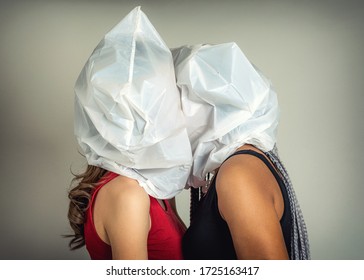 Faceless Portrait Of Two Young Kissing Girls With Plastic Bags On Their Heads. Lovers