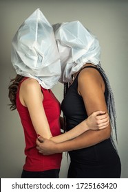 Faceless Portrait Of Two Young Kissing Girls With Plastic Bags On Their Heads. Lovers