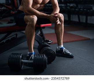 Faceless shirtless man sitting on a bench and resting after a workout.  - Powered by Shutterstock