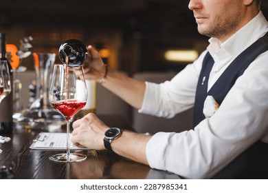 Faceless sommelier pours red wine into stem glass. - Powered by Shutterstock