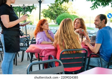 Faceless Waitress Taking An Order For A Group Of Mature Friends In A Restaurant. Group Of People Ordering Dinner At A Bar.