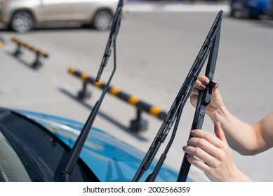 Faceless woman changing car windshield wipers.