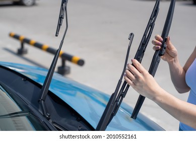 Faceless woman changing car windshield wipers.