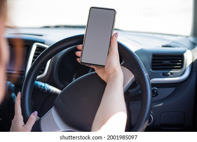 A faceless woman uses a mobile phone while driving a car. The girl uses the navigation in the smartphone