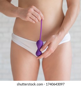 Faceless Woman In White Panties And With A Bare Tummy Holds A Kegel Trainer. Latex Vaginal Vibrator For Training The Pelvic Floor Muscles With An Antenna. The Device For Imbuilding. Women Health.