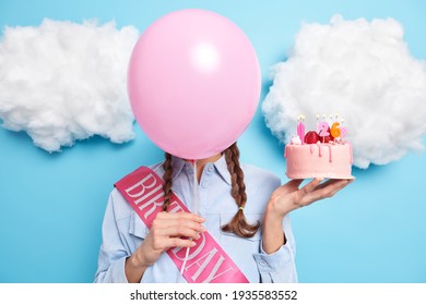 Faceless young woman hides behind helium balloon holds sweet dessert celebrates birthday dressed in festive clothes isolated over blue background with white clouds. Party celebration concept - Powered by Shutterstock