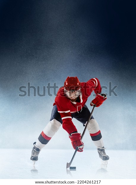 Face-off. Professional ice\
hockey player in red uniform and helmet in action on white blue\
snow backgound. Winter sports, competitions, energy, power. Poster\
for ad, design.