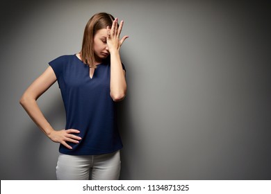 Facepalm! Disapoppointed and upset young woman against grey wall.