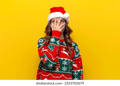 facepalm gesture. puzzled girl in christmas sweater and santa claus hat covers her face with her hand on yellow isolated background, displeased and tired woman shows boredom in new year's clothes - Powered by Shutterstock