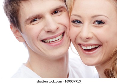 Faces of amorous young couple looking at camera with toothy smiles