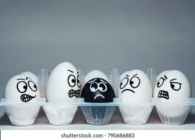 Faces on chicken eggs in the form of facial expressions, reflecting emotions. The concept of racism, misunderstanding, a barrier in relations, denial of society. Barriers between people, prejudice.