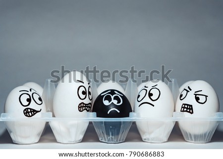 Faces on chicken eggs in the form of facial expressions, reflecting emotions. The concept of racism, misunderstanding, a barrier in relations, denial of society. Barriers between people, prejudice.