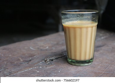 Faceted Glass Indian Masala Tea On A Wooden Board. Milk Chay In A Street Shop.