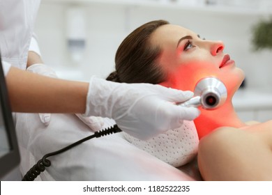 Facial Beauty Treatment. Woman Doing Red Led Light Therapy 