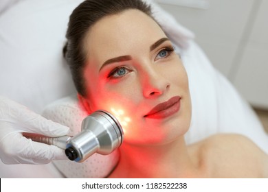 Facial Beauty Treatment. Woman Doing Red Led Light Therapy 