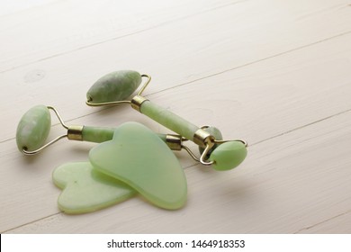 Facial and body stone massage instruments on light wooden background